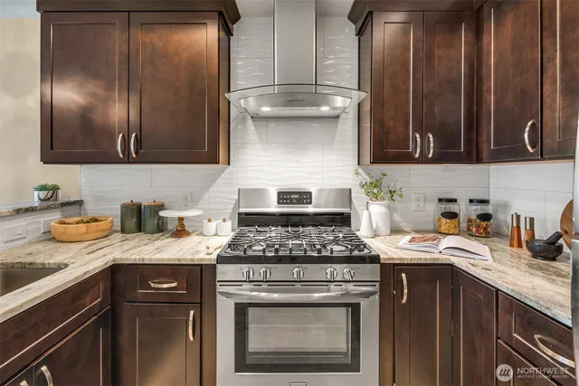 a kitchen with granite countertop stainless steel appliances a stove sink and cabinets