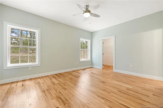 an empty room with wooden floor and windows