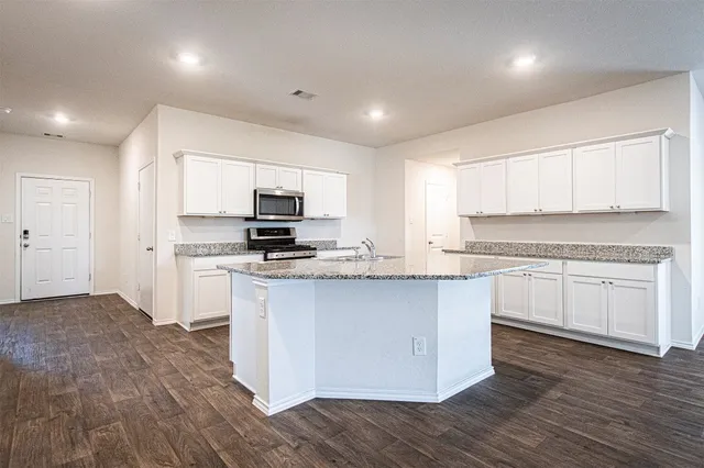 a kitchen with granite countertop white cabinets and appliances