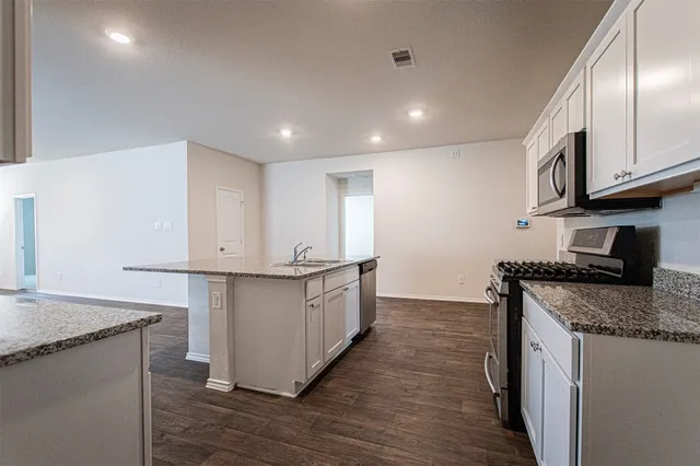 a large kitchen with stainless steel appliances granite countertop a stove a sink and a refrigerator