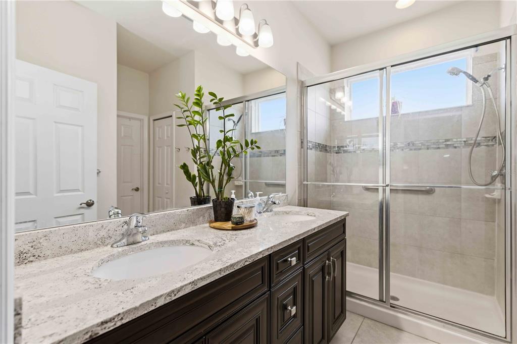10920 79th Street East Parrish, FL 34219 - Photo 36 of 73 a bathroom with a granite countertop sink a large mirror and a shower