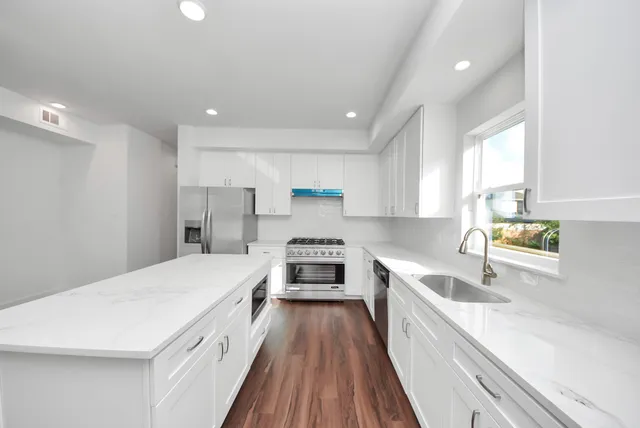 a kitchen with a sink a counter top space stainless steel appliances and a window