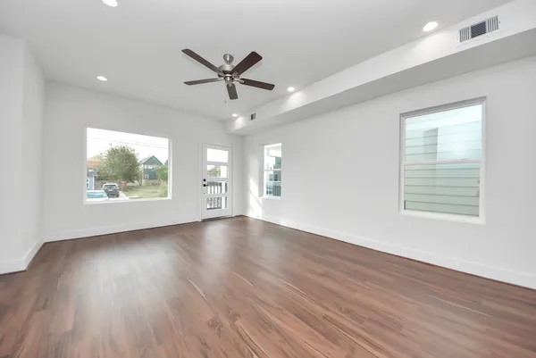 a view of an empty room with wooden floor and a window