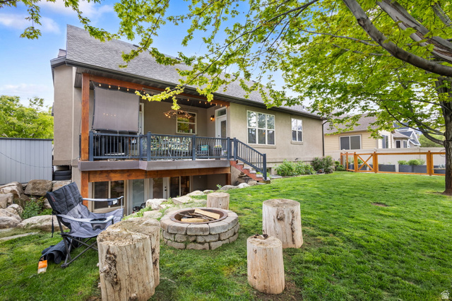 882 Sego Lily Way Mapleton, UT 84664 - Photo 33 of 41 Spacious backyard featuring a stone fire pit, a large grassy area, mature trees, and a multi-level deck with string lighting
