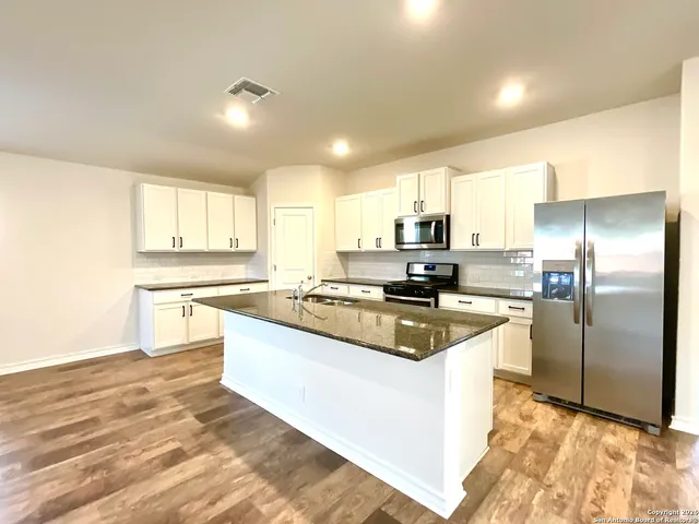a kitchen with stainless steel appliances granite countertop a sink a stove a refrigerator and cabinets