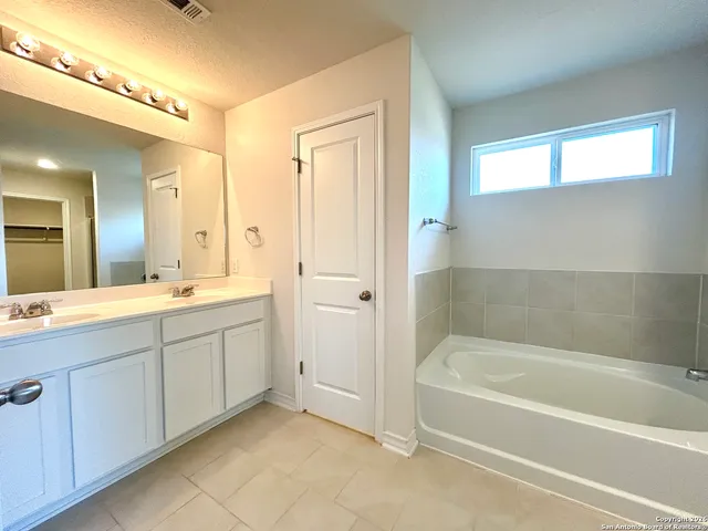 a spacious bathroom with a tub sink and mirror