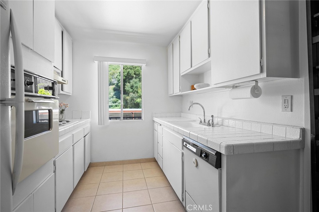 1935 Alpha Road, Unit 214 Glendale, CA 91208 - Photo 13 of 29 a kitchen with stainless steel appliances granite countertop a sink and dishwasher a stove with wooden cabinets