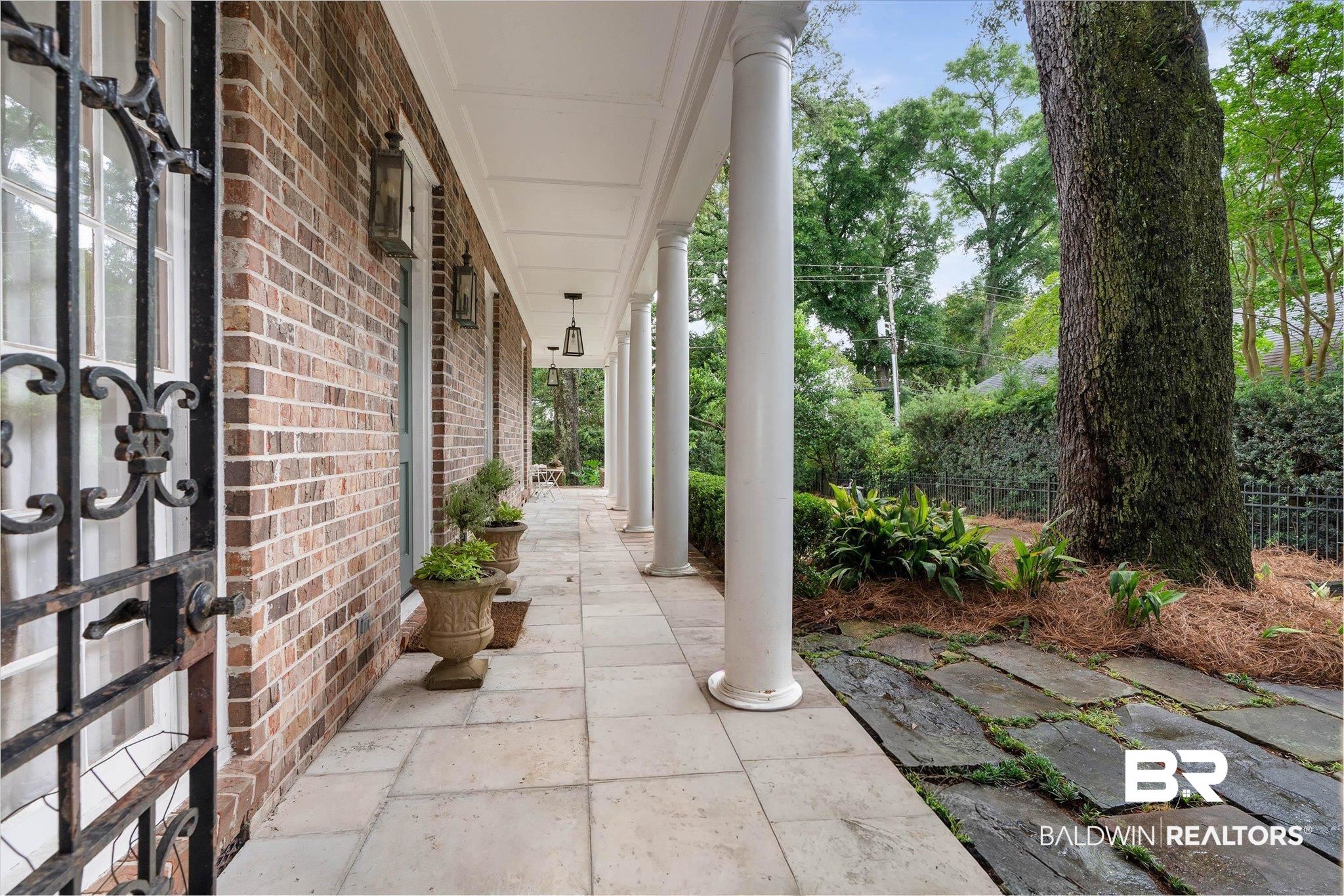 3908 Yester Place Mobile, AL 36608 - Photo 41 of 45 Brick exterior with a covered porch featuring multiple pillars, overhead lighting, and a flagstone pathway