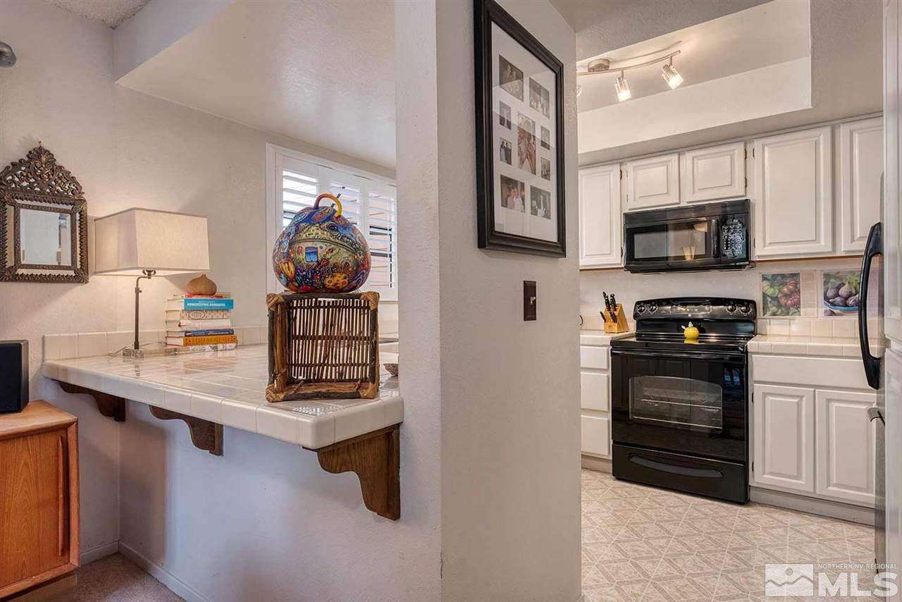 2875 Idlewild Drive, Unit 58 Reno, NV 89509 - Photo 8 of 25 a kitchen with stainless steel appliances kitchen island granite countertop a stove a sink and a microwave