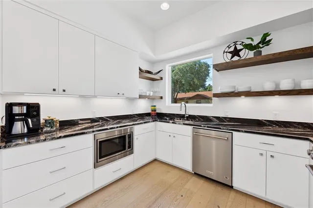 a white kitchen with stainless steel appliances granite countertop white cabinets a sink and dishwasher