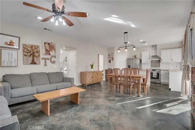 a living room with furniture kitchen view and a chandelier