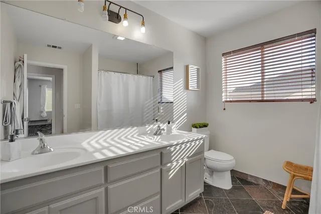 a bathroom with a granite countertop sink a toilet and a mirror