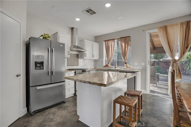 a kitchen with stainless steel appliances granite countertop a refrigerator a sink a stove and a refrigerator