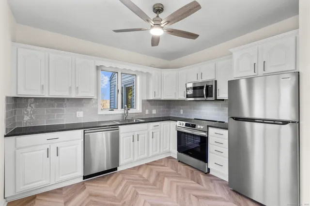 a kitchen with granite countertop stainless steel appliances a refrigerator a sink a stove a microwave a center island and cabinets