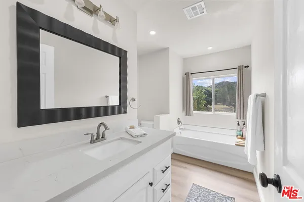 a bathroom with a double vanity sink mirror and a bathtub