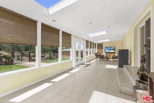 a view of a hall with floor to ceiling windows and kitchen view