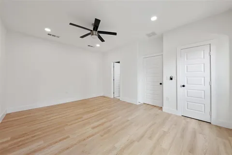 a view of empty room with wooden floor and ceiling fan