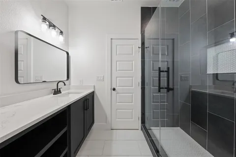 a en suite bathroom with a shower sink and mirror