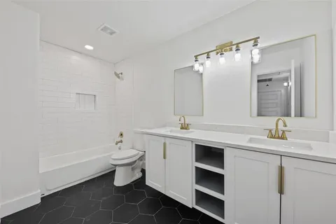 a bathroom with a double vanity sink toilet and mirror