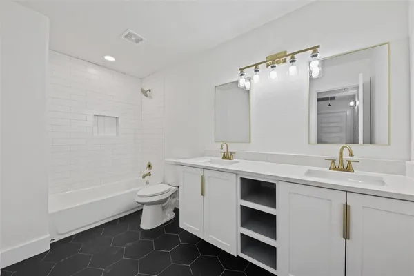 a bathroom with a double vanity sink toilet and mirror