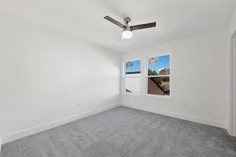 an empty room with a window and ceiling fan