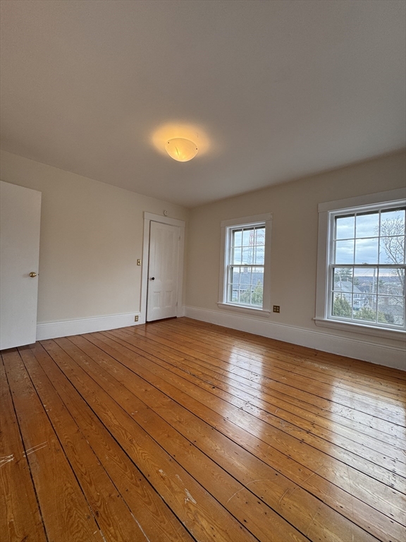 68 Cottage Street, Unit 68 Newton, MA 02464 - Photo 11 of 16 an empty room with wooden floor and windows