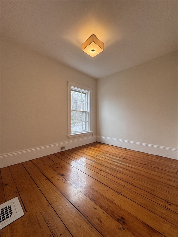 68 Cottage Street, Unit 68 Newton, MA 02464 - Photo 13 of 16 an empty room with wooden floor and windows