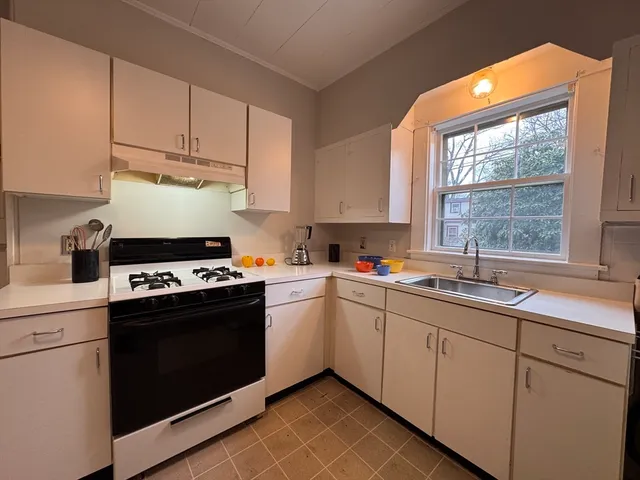 a kitchen with stainless steel appliances a stove a sink and white cabinets
