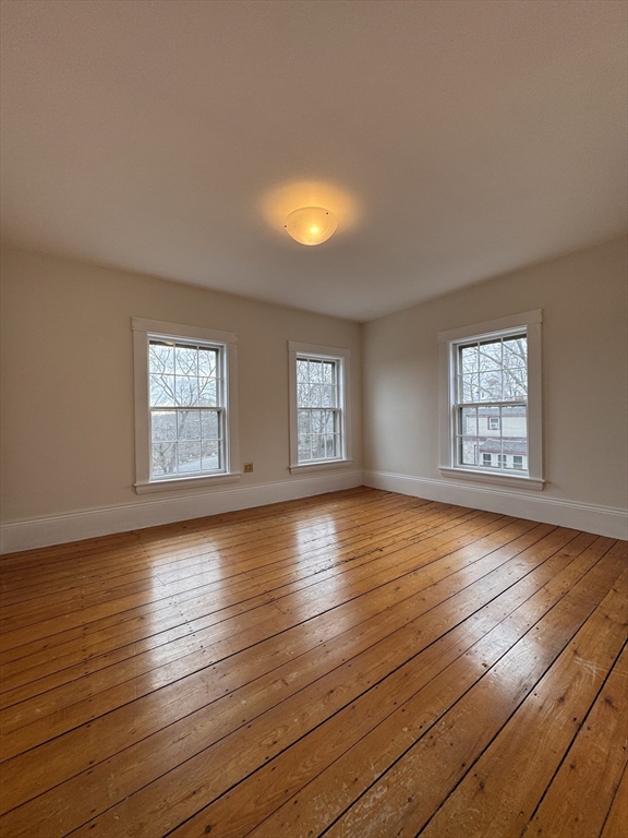 68 Cottage Street, Unit 68 Newton, MA 02464 - Photo 10 of 16 an empty room with wooden floor and windows