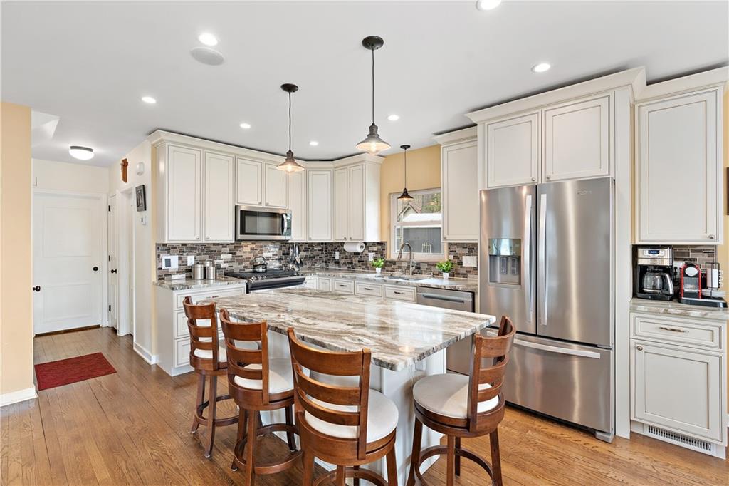 349 Backbone Road Sewickley, PA 15143 - Photo 7 of 25 a kitchen with stainless steel appliances a refrigerator a stove a sink and a dining table with wooden floor