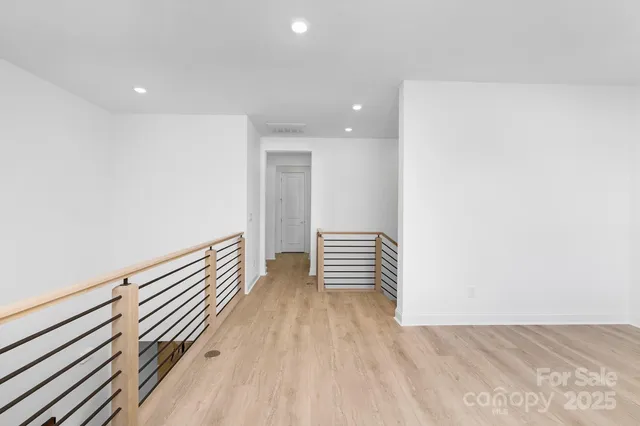 a view of a hallway with wooden floor and stairs