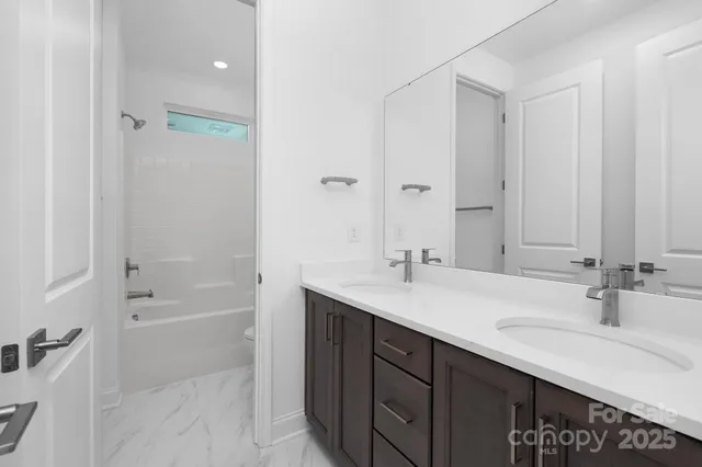 a bathroom with a sink double vanity granite tub shower and a mirror