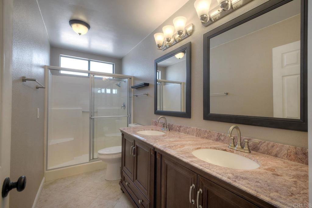 1394 Longfellow Road Vista, CA 92081 - Photo 28 of 50 a bathroom with a granite countertop sink a large mirror and a shower