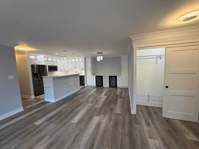 a big room with wooden floor and kitchen view