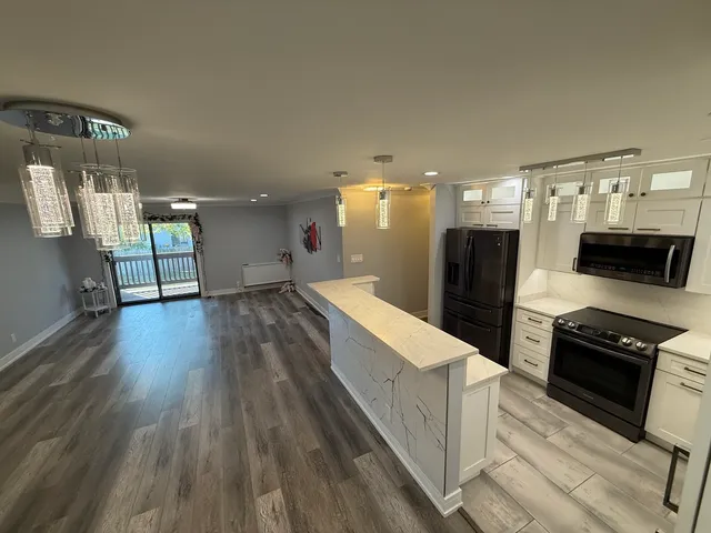 a kitchen with stainless steel appliances kitchen island granite countertop a stove a refrigerator a sink and dishwasher with wooden floor