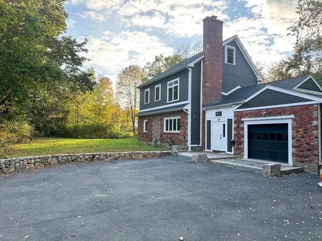 a view of a brick house with a big yard and large tree