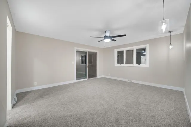 a view of an empty room with a chandelier fan