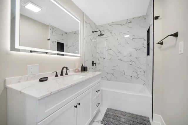 a bathroom with a bathtub a sink a vanity and a shower