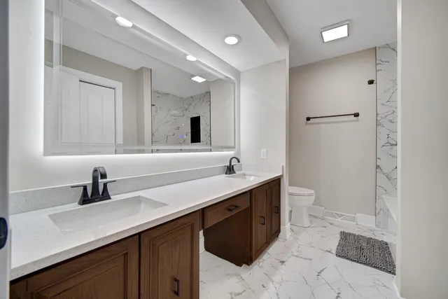 a bathroom with a double vanity sink toilet and mirror