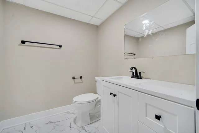 a bathroom with a granite countertop sink vanity mirror and toilet