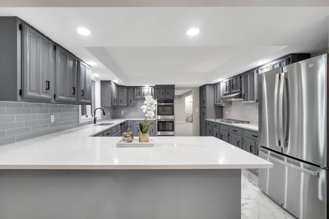 a kitchen with stainless steel appliances a sink a stove a refrigerator and cabinets