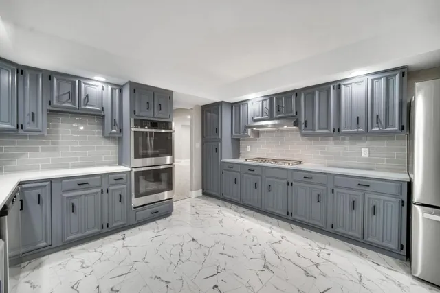 a kitchen with granite countertop a sink cabinets and stainless steel appliances