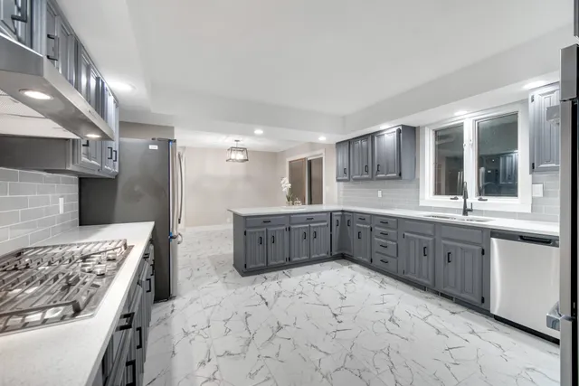 a kitchen with stainless steel appliances granite countertop a stove a sink and a refrigerator