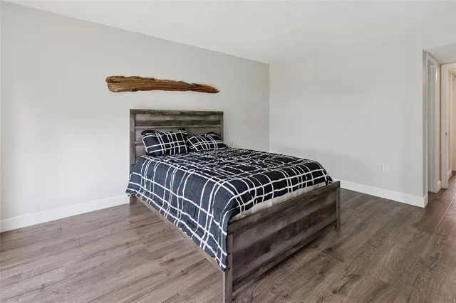 a spacious bedroom with a bed and wooden floor