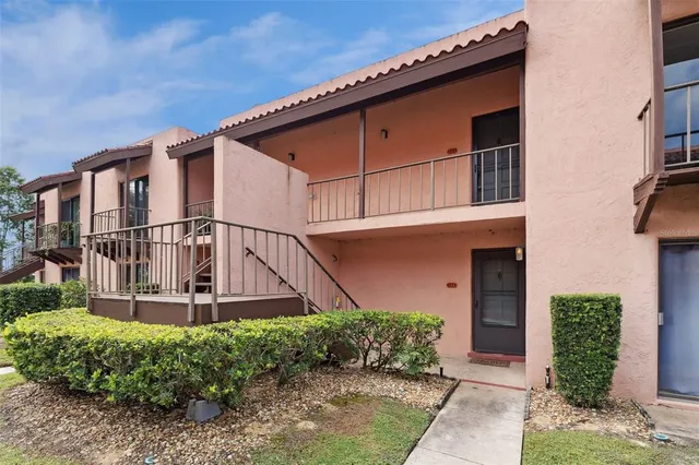 a view of a house with a small yard plants and large tree