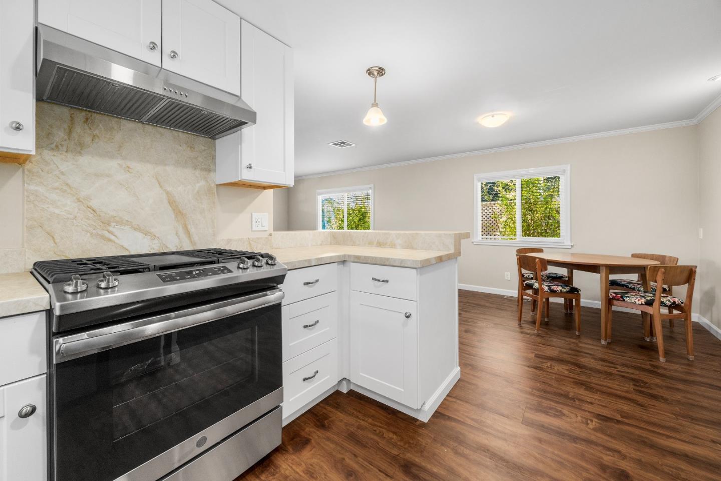 a kitchen with granite countertop wooden floor stainless steel appliances and dining table