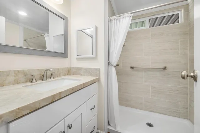a bathroom with a granite countertop sink a mirror and shower