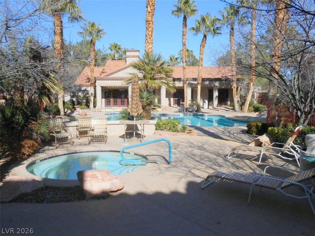 9325 West Desert Inn Road, Unit 132 Las Vegas, NV 89117 - Photo 31 of 36 A tranquil oasis awaits with a shimmering pool and relaxing spa, perfectly set amidst lush palm trees.