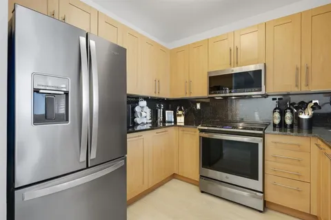 a kitchen with stainless steel appliances white cabinets a refrigerator and a stove