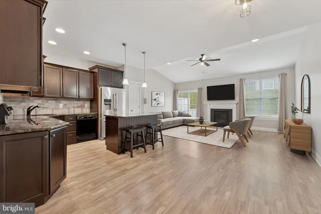 a kitchen with stainless steel appliances granite countertop a stove top oven a sink dishwasher a dining table and chairs with wooden floor